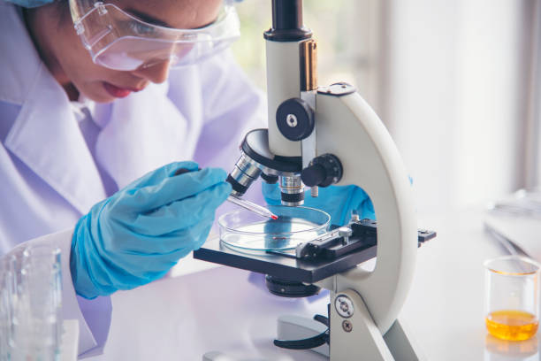 Laboratory technician examining a sample under a microscope to identify pathogens associated with respiratory disease