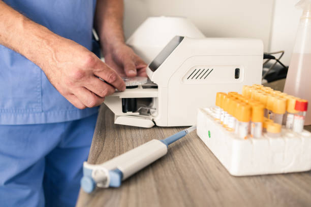 Nhân viên vận hành máy xét nghiệm máu thú y bên cạnh các ống mẫu trong phòng xét nghiệm